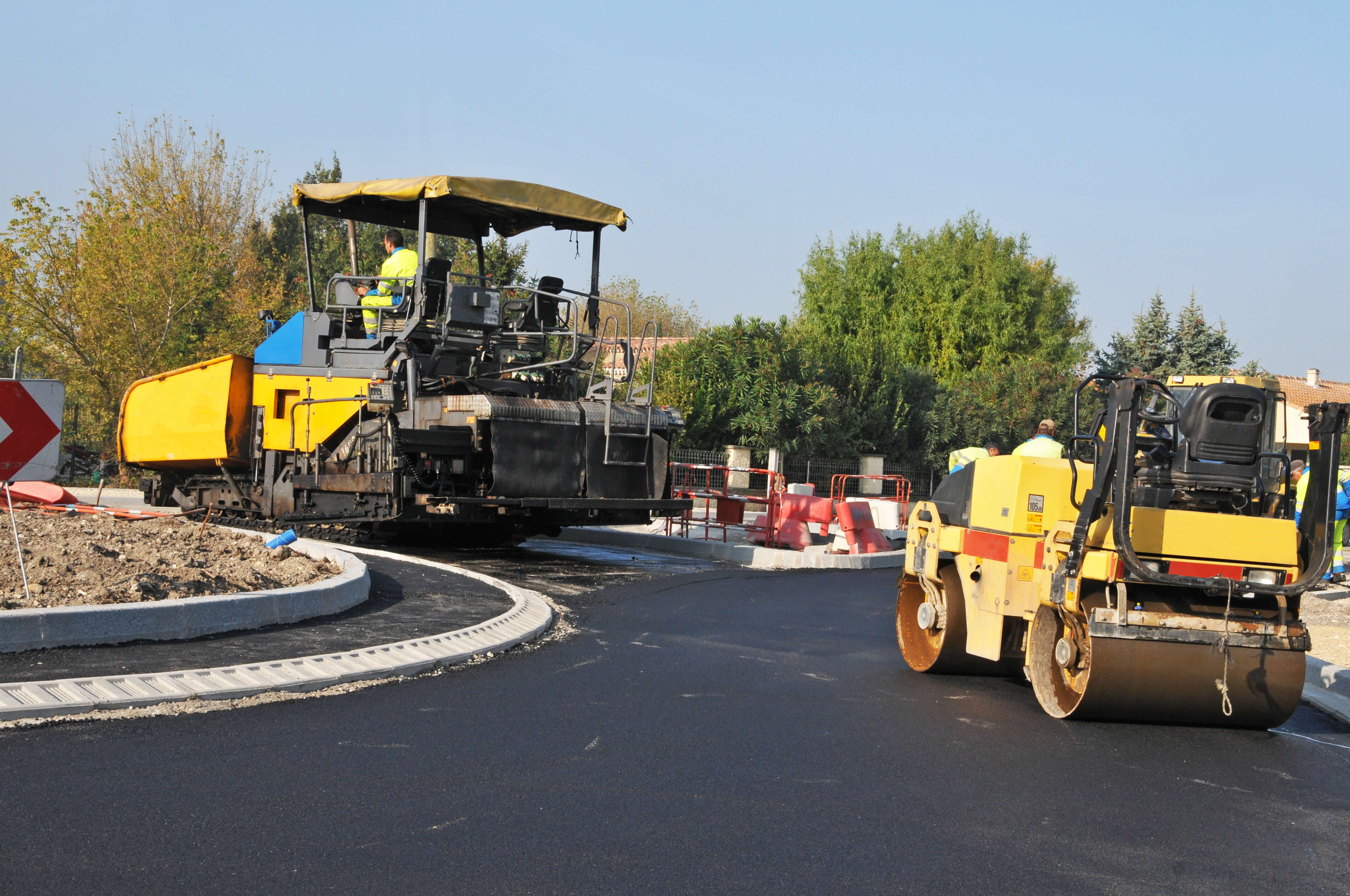Baumaschinen beim neuen Asphaltieren von einem Kreisverkehr